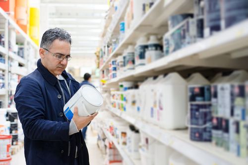 Choosing the Right Paint Sheen Homeowner Shopping for Paint in the Paint Aisle Of a Hardware Store.