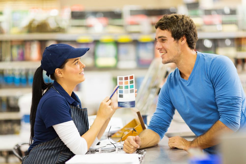 Female employee pointing out options on a paint sample card to a male customer Female employee pointing out options on a paint sample card to a male customer