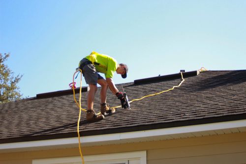 Roofing Lingo: A Homeowner's Guide Contractor In Safety Harness Using Caulk Gun On Roof